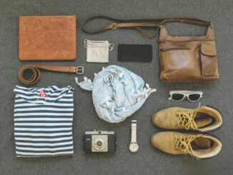 Vintage travel essentials flat lay with leather bags, shoes, camera, and clothing.