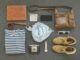 Vintage travel essentials flat lay with leather bags, shoes, camera, and clothing.