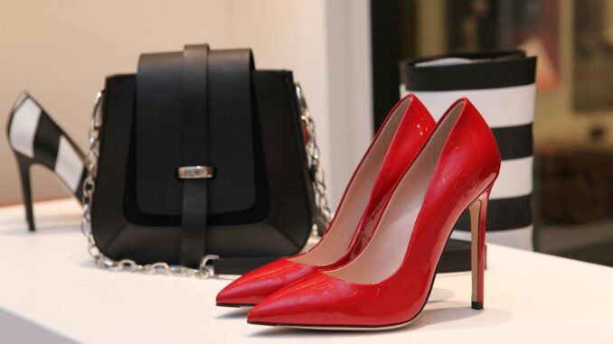 Showcasing sleek red stilettos and a chic black handbag in a luxury boutique setting.