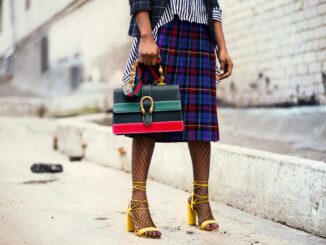 Fashion-forward outfit with plaid skirt and colorful handbag in urban setting.