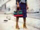 Fashion-forward outfit with plaid skirt and colorful handbag in urban setting.